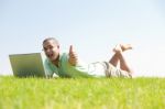 A Young Men Sit On The In The Park Using A Laptop Stock Photo