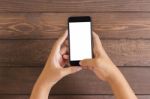 Phone In Woman Hand Showing White Screen On Wood Table, Mockup N Stock Photo