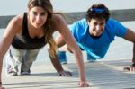 Couple Doing Push Ups Near The Sea Stock Photo