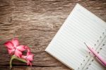 Surface Of A Wooden Table With Notebook, Desert Rose. Vintage Style Stock Photo