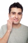 Young Man Applying Cream Lotion Stock Photo