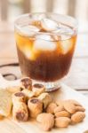 Glass Of Black Iced Coffee With Some Snack Stock Photo