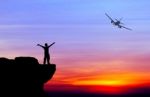 Silhouette Of A Man On The Rock And Silhouette Commercial Plane Stock Photo