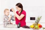 Mother Feeding Child In Kitchen Stock Photo