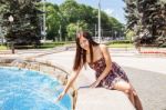 Young Beautiful Brunette Sitting By The Fountain Stock Photo