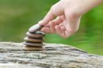 Hand Put Stone Building A Pile Of Zen Stones Stock Photo