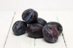 Tasty Purple Plums Isolated On A White Wooden Background Stock Photo