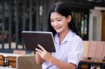 Portrait Of Thai High School Student Uniform Beautiful Girl Using Her Tablet Stock Photo