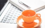 Laptop With Coffee Cup And Notepad On Desk Stock Photo