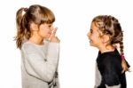 Little Girl Telling Her Sister To Shut Up With Her Finger On The Mouth. A Gesture Of Silence . Closeup-isolated On White Background Stock Photo