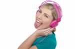 Woman With Headphones On Sticking Her Pierced Tongue Out Stock Photo