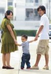 Parents Holding Hand Of His Son In Outdoors Stock Photo