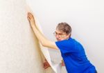 Elderly Worker Attaching Wallpaper Stock Photo