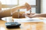 Estate Agent Giving House Keys To Man And Sign Agreement In Offi Stock Photo