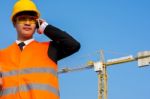 Close Up Young Engineer In Orange Shirt Stands Talking On A Mobi Stock Photo