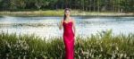 Beautiful Young Woman In The Gardens Wearing A Long Silk Red Dress Stock Photo