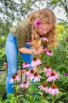 Young Caucasian Woman Smelling Echinacea Flower In Garden Stock Photo