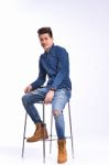 Male Model In Denim Jeans Sitting On A Chair . Studio Shoot Stock Photo