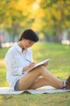 Young Beautiful Asian Woman Writing Text In Diary Book In Yellow Stock Photo