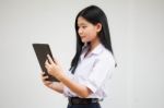 Portrait Of Thai High School Student Uniform Beautiful Girl Using Her Tablet Stock Photo