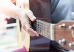 Woman's Hands Playing Acoustic Guitar Stock Photo