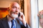 Middle-aged Businessman Listening On Smartphone At Home Stock Photo