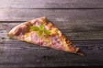 Piece Of Basil On Hot Pizza, Wooden Background Stock Photo