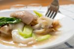 Rad Na, Famous Thai Chinese Style Wide Rice Noodle Dish With Tasty Tender Pork With Thick Gravy Sauce. Close Up With Fork Stock Photo