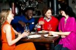 Four Friends Enjoying Dinner At A Restaurant Stock Photo