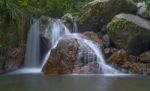 Small Waterfall With Red Big Stone In The Forest Stock Photo