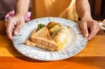 Woman Hand Holding White Plate With Omelet Potato, Tomatoes Parsley And Feta Cheese And Bread On Wooden Table. Eating Breakfast Stock Photo