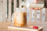 Pouring Milk To Iced Glass Of Coffee Stock Photo