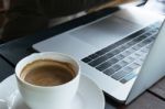 Coffee And Blur Laptop On Table Wood Background In Cafe Stock Photo