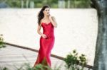 Beautiful Young Woman In The Gardens Wearing A Long Silk Red Dress Stock Photo