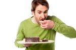 Young Man Tasting Chocolate Cake In Hurry Stock Photo