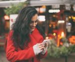 Woman In Red Coat Read Good News On Smartphone In Hands, Urban S Stock Photo