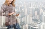 Double Exposure Of Woman Using Tablet Technology And Urban Building Background Stock Photo