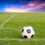 Soccer Ball On Soccer Field Against Sunset Sky Stock Photo