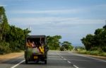 People Traveling In The Back Of A Crammed Vehicle Down A Road In Stock Photo