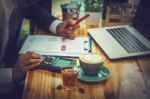 Business Man Sitting On A Calculator To Figure Out In A Coffee S Stock Photo