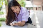 Portrait Of Thai High School Student Uniform Teen Beautiful Girl Using Her Phone And Smile Stock Photo