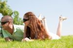 Beautiful Young Couple Lie Down On Grass Stock Photo