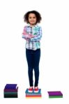 Confident School Child Standing On Books Stock Photo