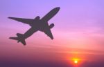 Silhouetted Commercial Airplane Flying At Sunset Stock Photo