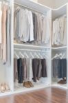 Dress And Shirts Hanging On Rail In White Wardrobe Stock Photo