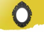 Oval Black Picture Frame With A Decorative On Yellow Wall Stock Photo