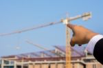 Young Engineer In Orange Shirt Stands Pointing At A Building Bei Stock Photo