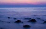 Soft Waves On A Rocky Beach In The Evening Stock Photo