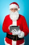 Modern Santa Using Digital Touch Screen Device Stock Photo