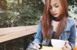 Happy Young Woman Drinking Coffee Outdoors And Using Smartphone Stock Photo